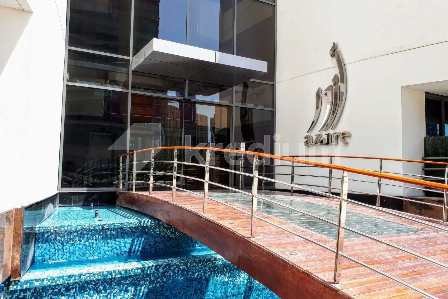 Bridge over a swimming pool leading to a modern building entrance