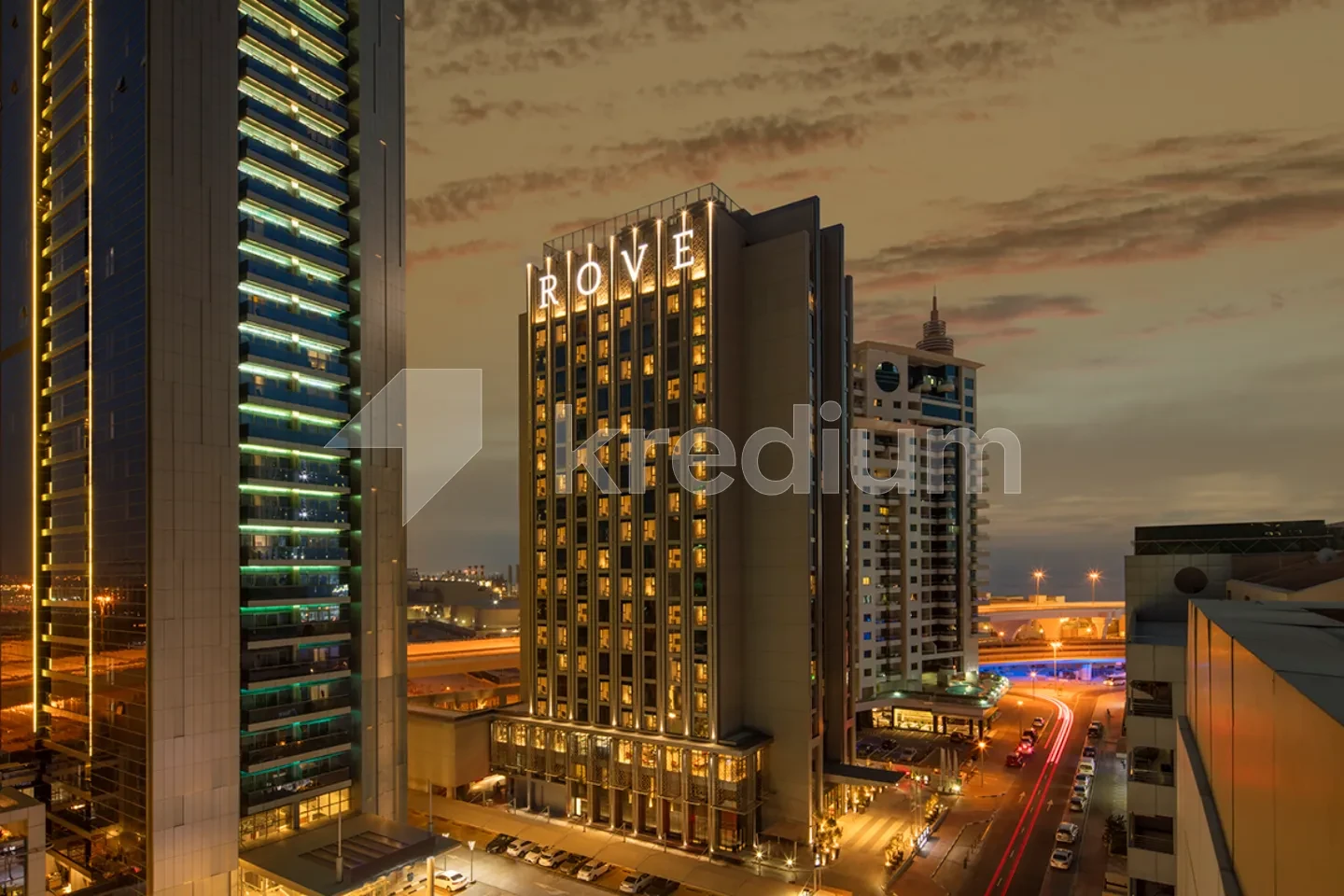 A night image of a stylish tall building with a rove sign on top