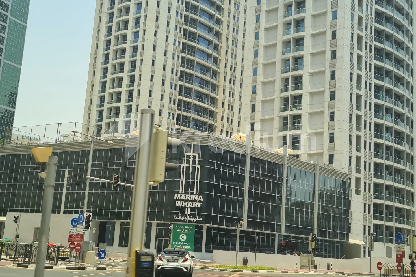A glass mid-rise building with a Marina Wharf sign in the center