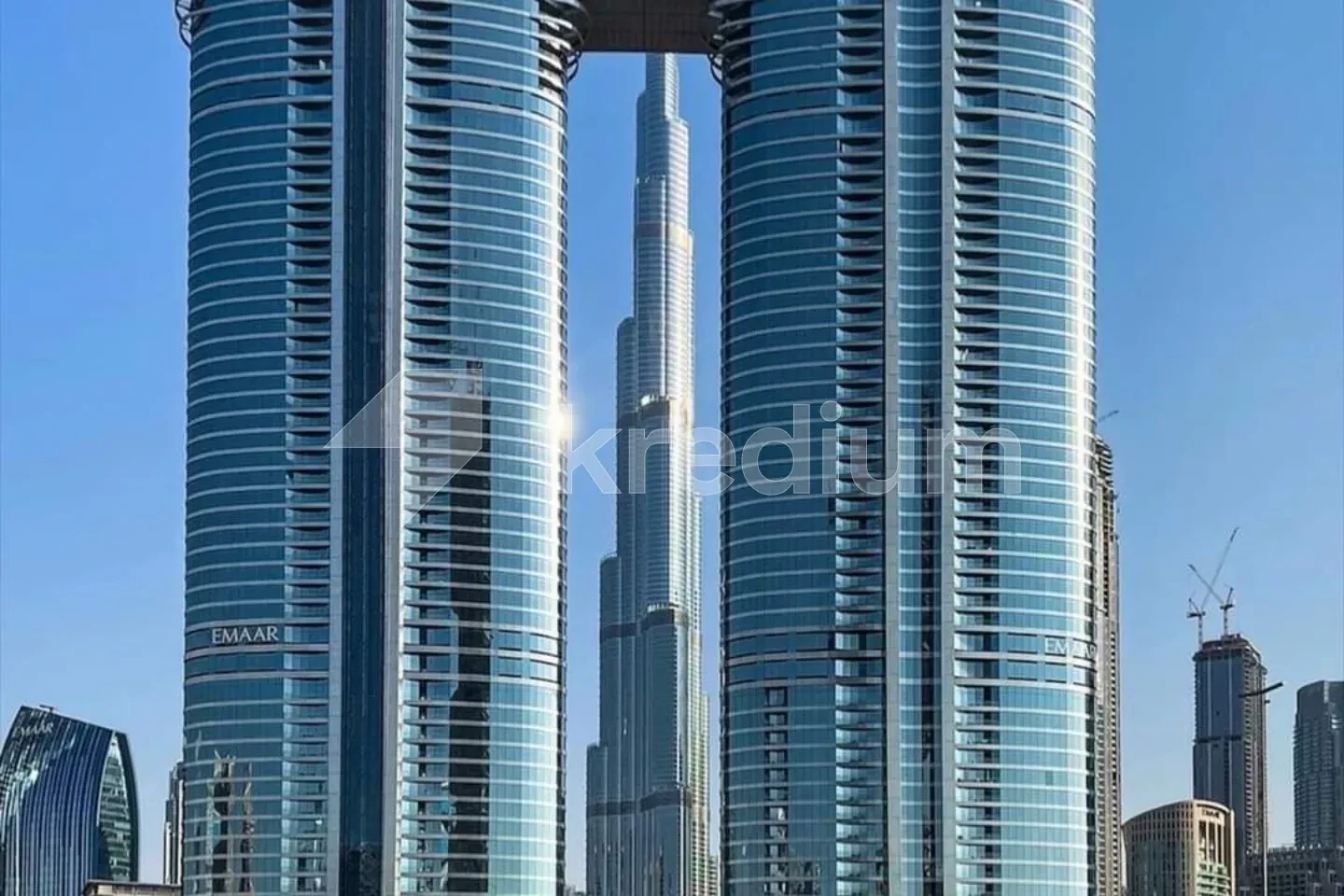 Two round glass towers with the Burj Khalifa building in the background