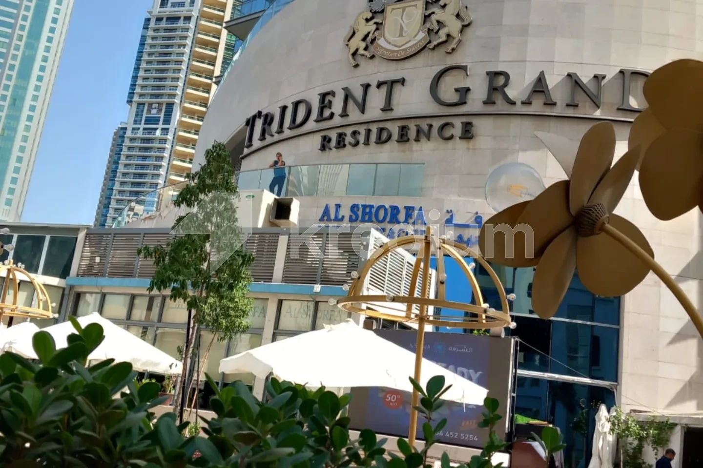 Entrance to a modern building with a sign saying Trident Grand Residence