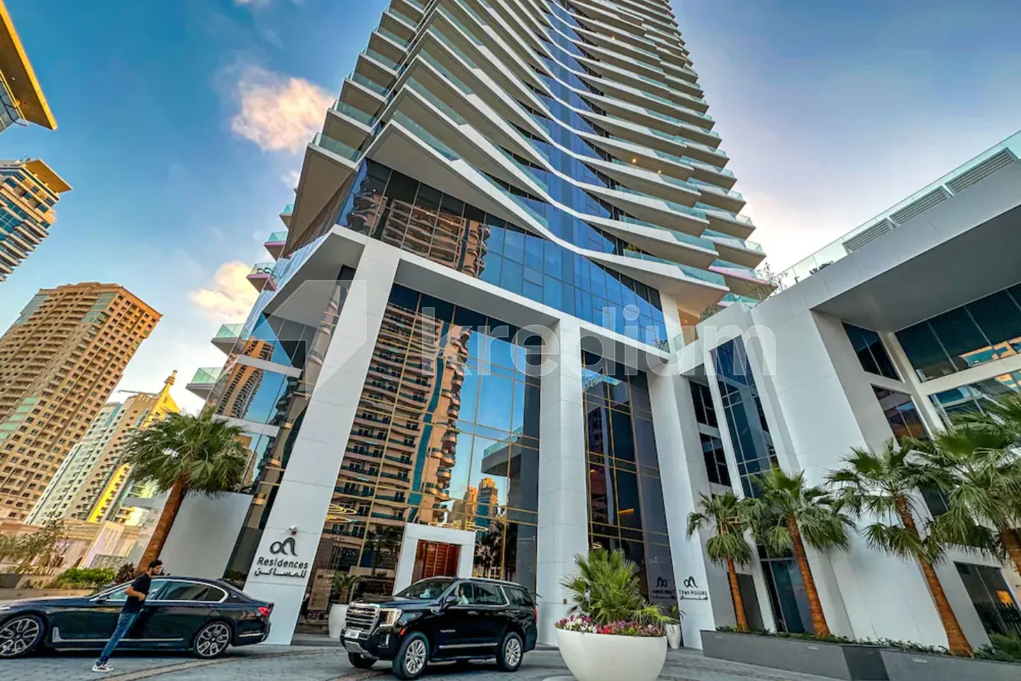 Luxurious glass tower with black cars and palm trees in front of it