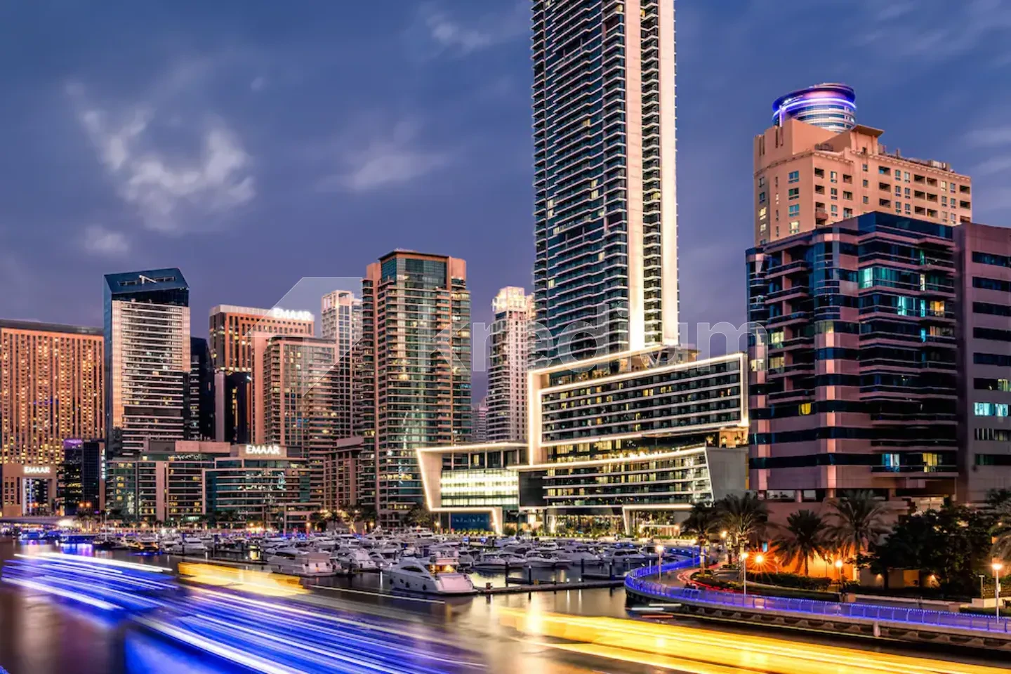 A night image of luxurious glass buildings next to a busy road