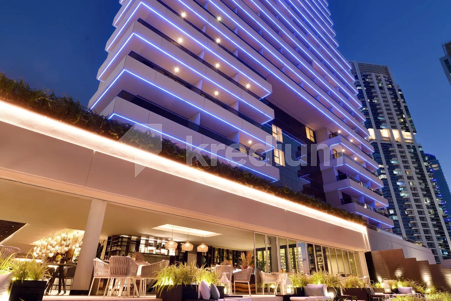 Night image of a modern tower with a cafe at the base floor