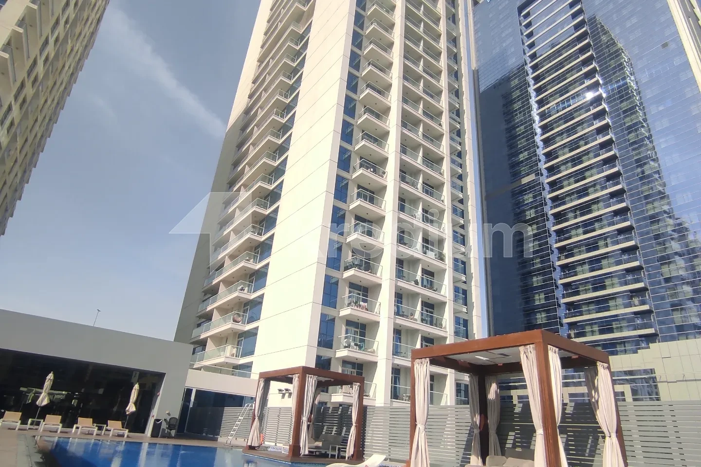 A white high-rise sleek building overlooking a pool