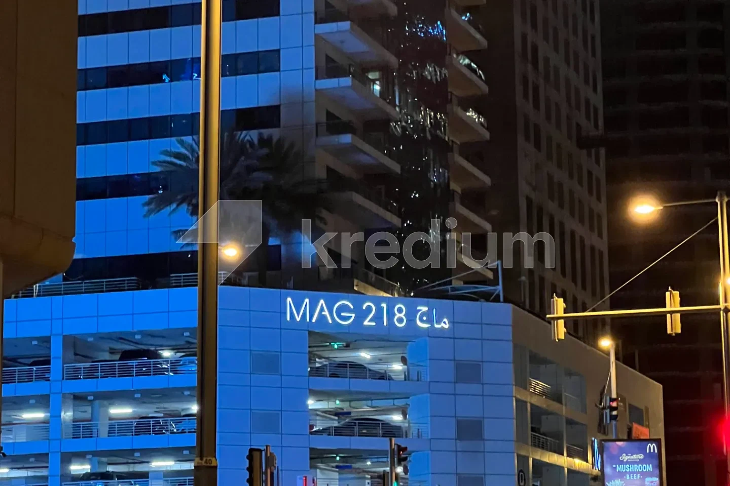 A night image of a modern building with a MAG 218 sign