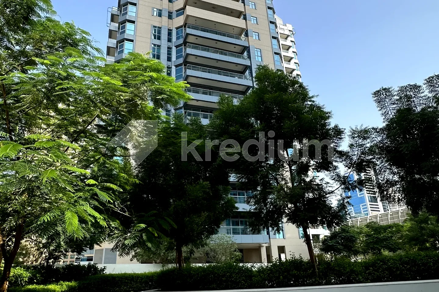 A glass mid-rise building with trees in front of it