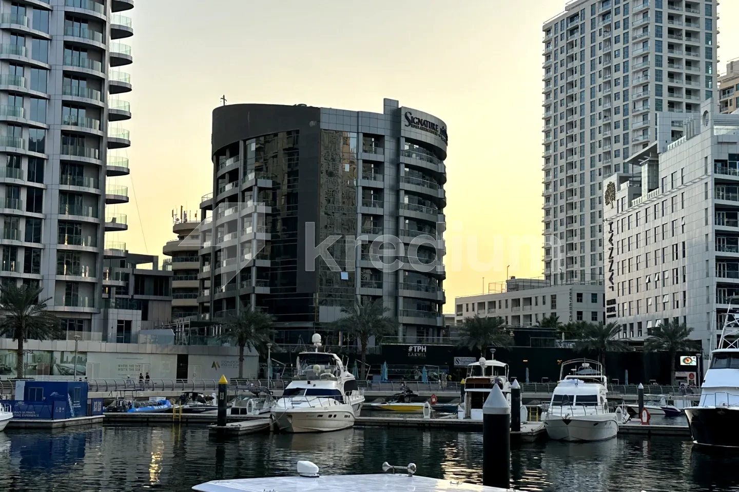 A modern round mid-rise building overlooking a port