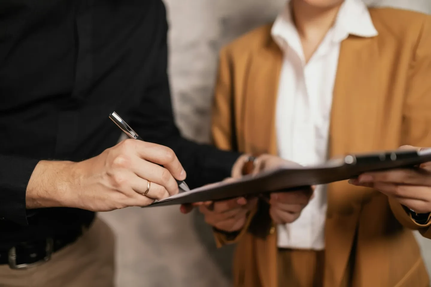 A real estate agent holding a document while a person is signing it.
