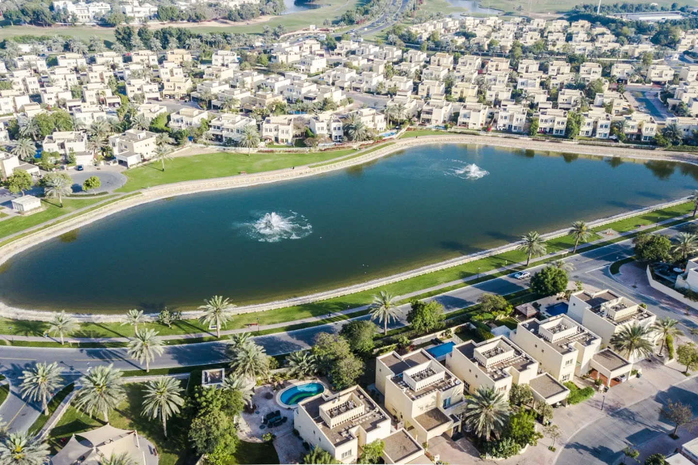 A residential area with houses surrounding a lake in Dubai.