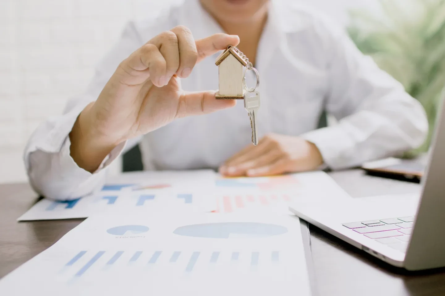 A hand holding a house keychain with a key.