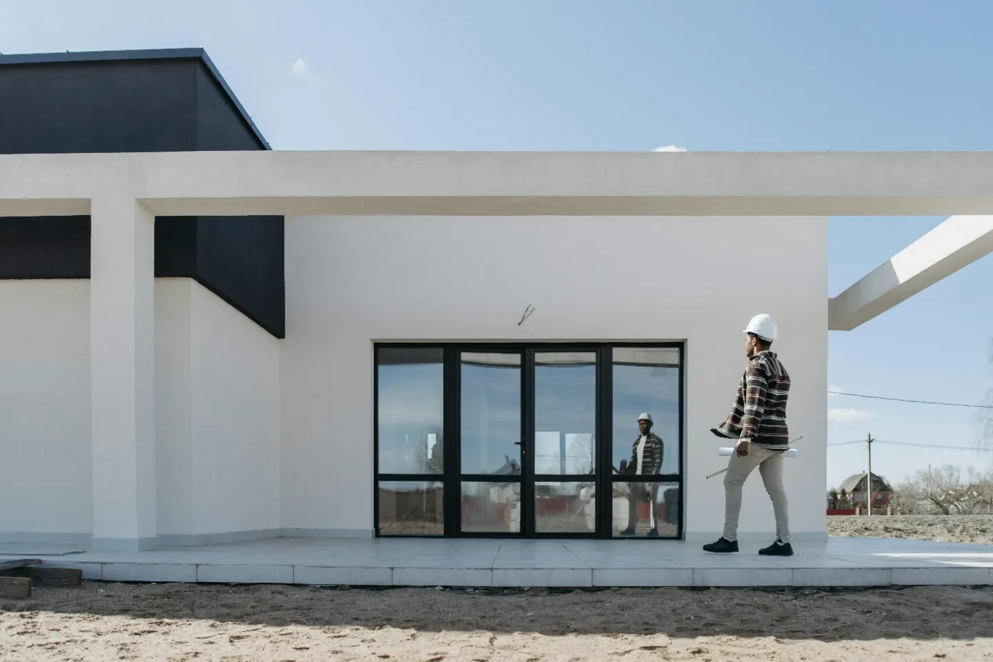A person with a white helmet checking out the exterior of a modern residential building.
